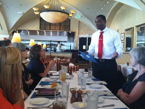 Monte talking to four women at a restaurant table.